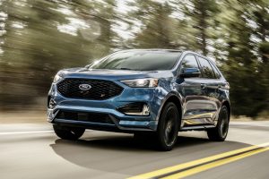 blue 2019 Ford Edge ST driving along a tree-lined road