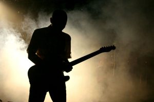 dark outline of a guitar player with fog in the background