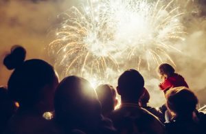 Shadowed silhouettes of people watching a fireworks display