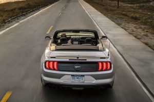 rear view of a silver 2019 Ford Mustang convertible driving along a coastal highway