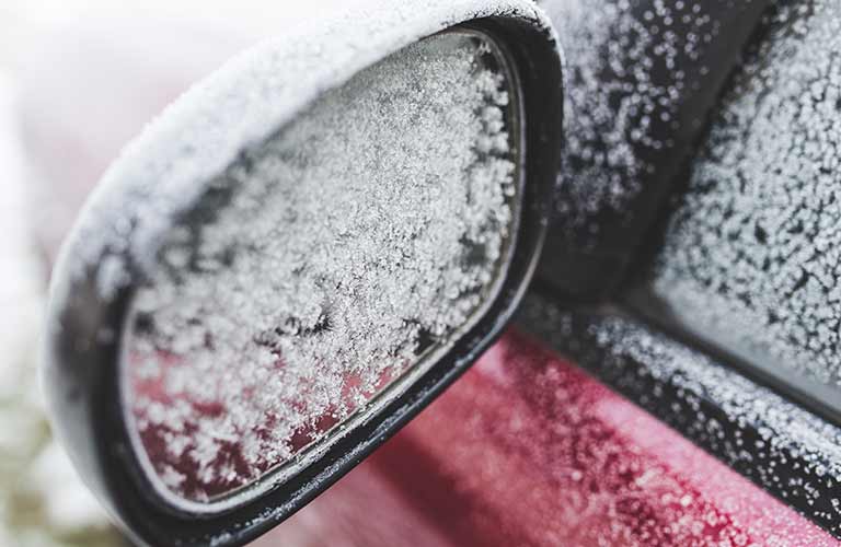 Ice-covered side mirror on red vehicle
