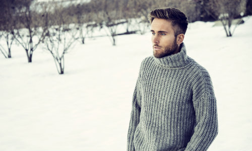 Pensive man standing outside in winter and wearing sweater