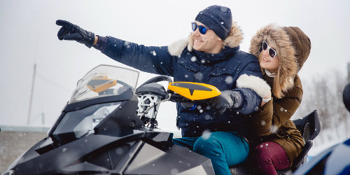 Two snowmobile drivers pointing at scenery surrounding them