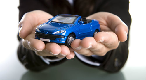 Hands holding small car to illustrate insurance coverage