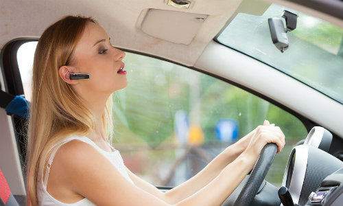 Woman speaking into bluetooth headset while driving