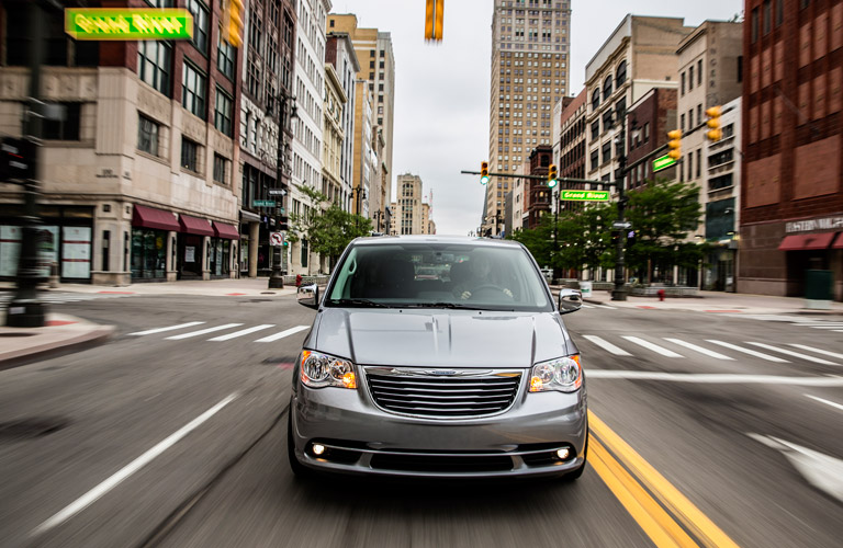 Silver Chrysler Town and Country minivan driving on city street