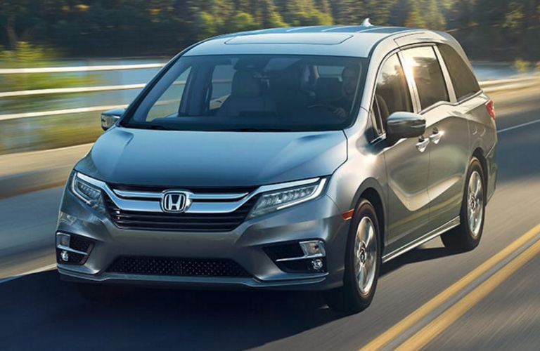 Front view of silver Honda Odyssey minivan driving on empty road