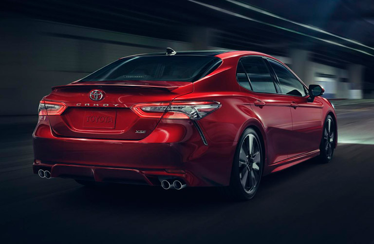 Rear view of red 2018 Toyota Camry driving on dark street