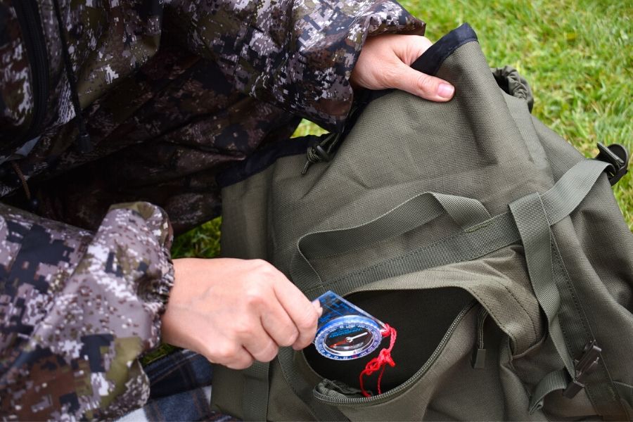 Person loading compass into backpack