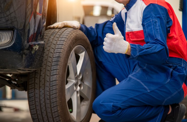 Mechanic giving thumbs up next to tire