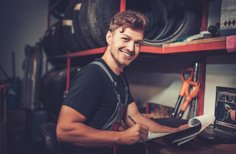 A mechanic smiles and fills out a form.