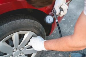 person checking a car's tire pressure