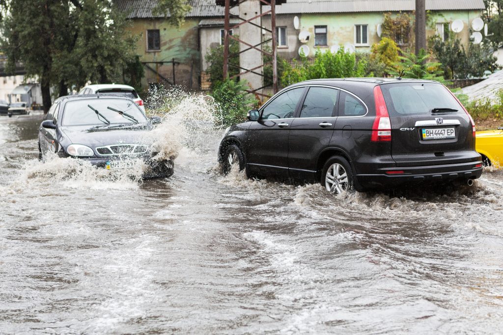 Driving cars on a flooded road during flooding caused by torrential rains. Cars float on water flooded streets.