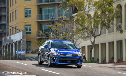 2018 Kia Rio blue driving on a street in a city in the day sunlight