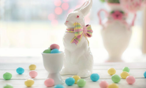 ceramic bunny sculpture surounded by minature candy eggs on a table
