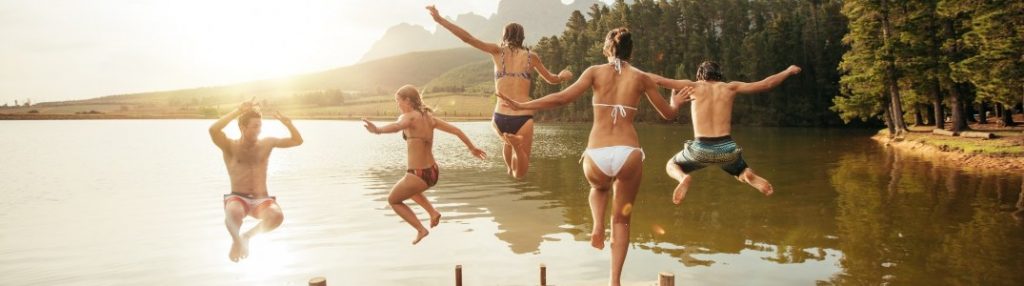 A family jumping into a large lake