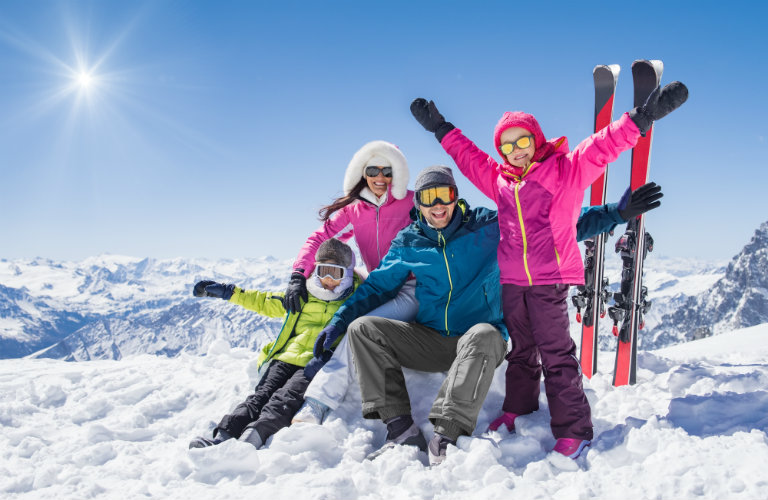 Family-of-skiers-posing-on-mountain