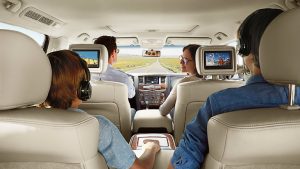 family happily sitting in nissan armada, kids watching tv on headrest monitors