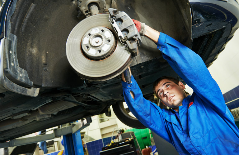 Car-mechanic-examining-cars-wheels-on-lift
