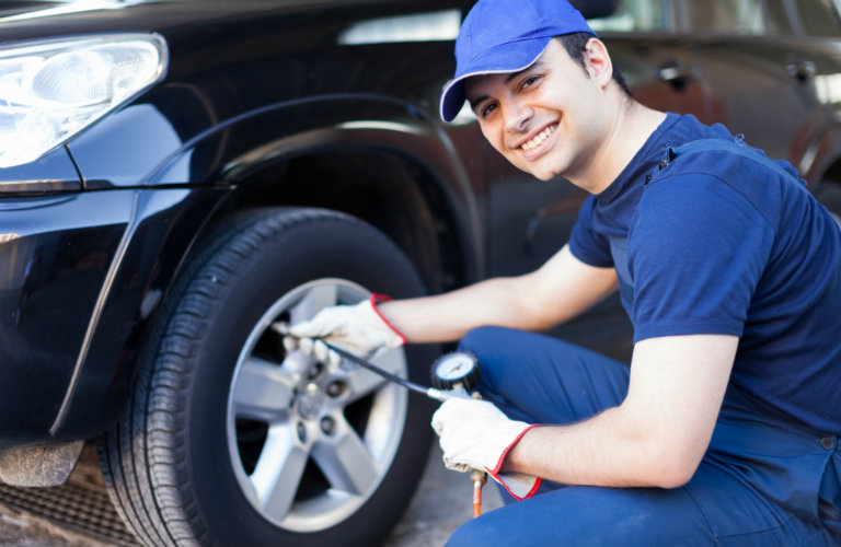 Smiling-mechanic-inflating-cars-tire