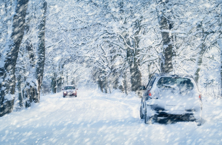 Two-cars-driving-down-snow-covered-road