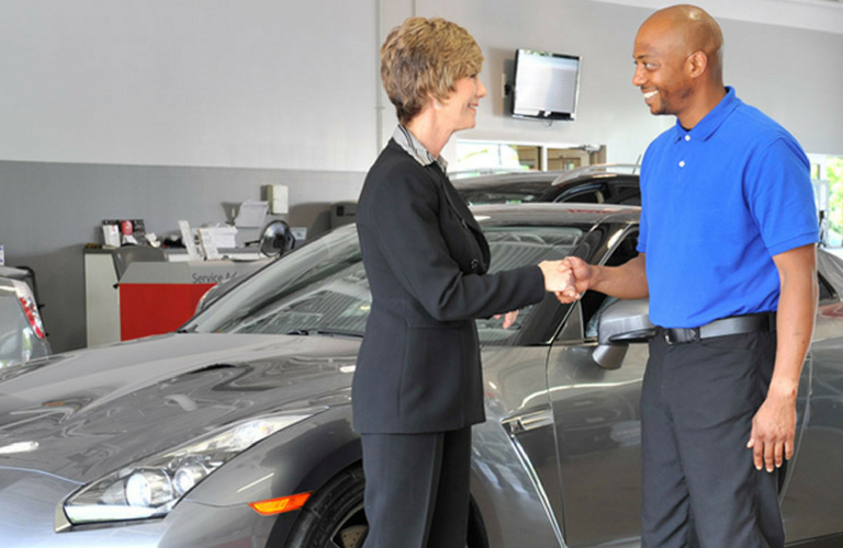 Team members of a Nissan dealership with customer