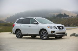 right side view of white nissan pathfinder parked on dirt