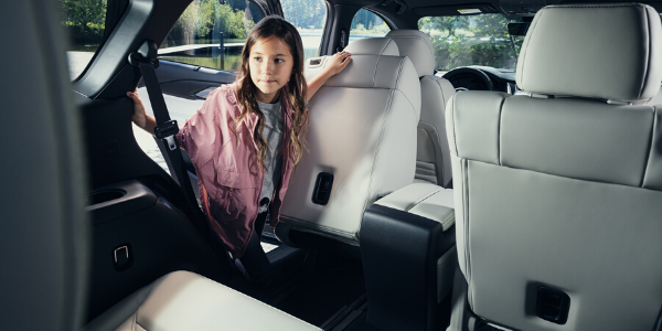 Young girl accessing the third-row seats of the 2020 Mazda CX-9 with second-row seat sliding forward