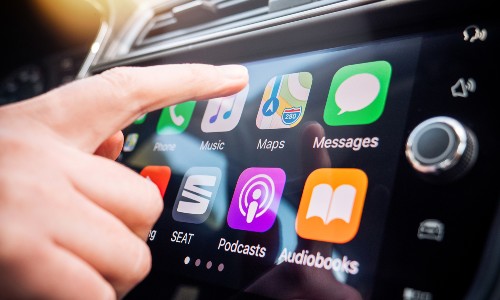 finger about to touch apple carplay display on car screen