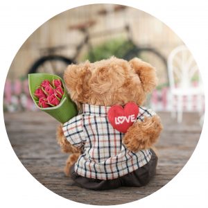 Teddy bear holding flowers and heart behind its back