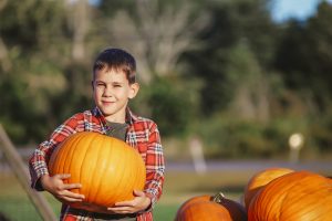young boy carrying a pumpkin