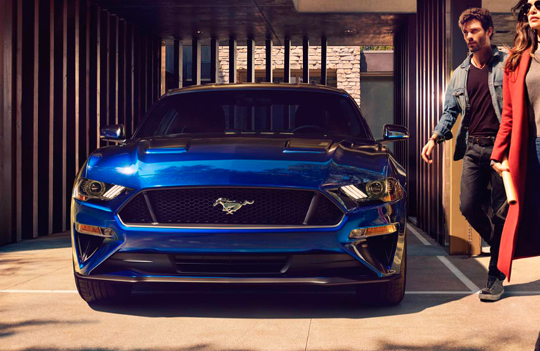 Man and Woman Stand Next to Blue Ford Mustang